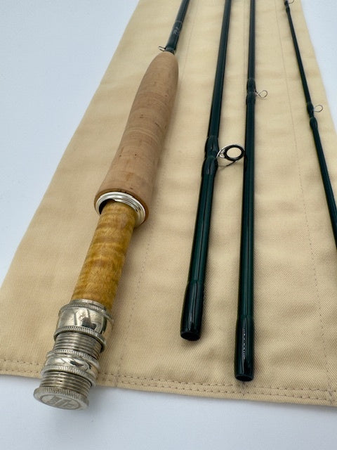 Winston Pure 9' 4wt fly fishing rod with cork handle and green sections, displayed elegantly on a beige background.